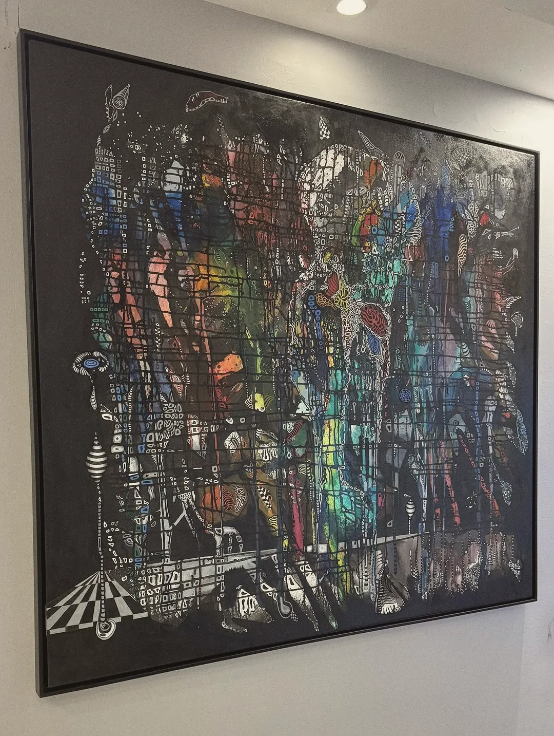 Grande tela abstrata emoldurada em preto numa parede clara