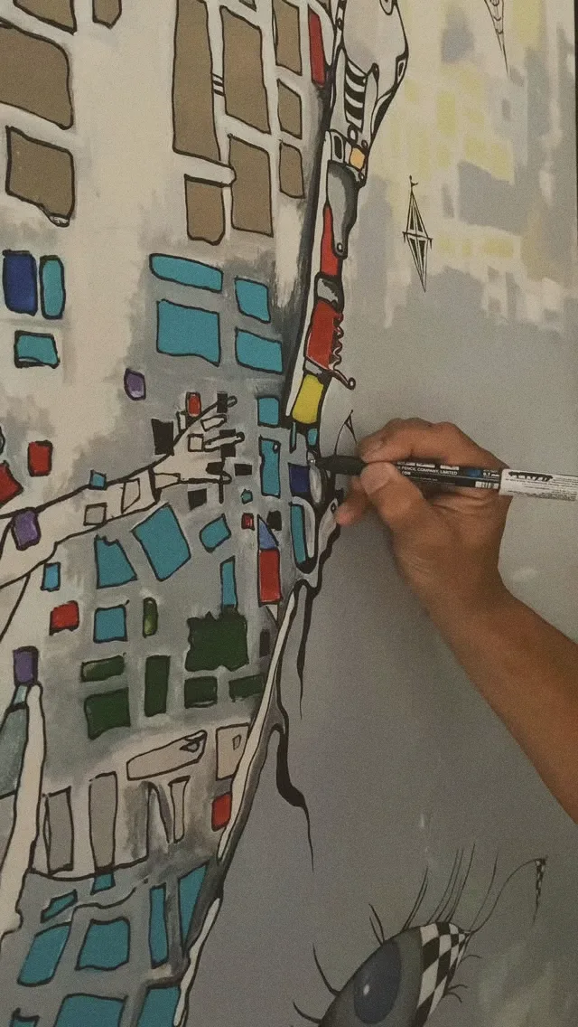 Mão do artista desenhando com caneta preta sobre blocos de cor